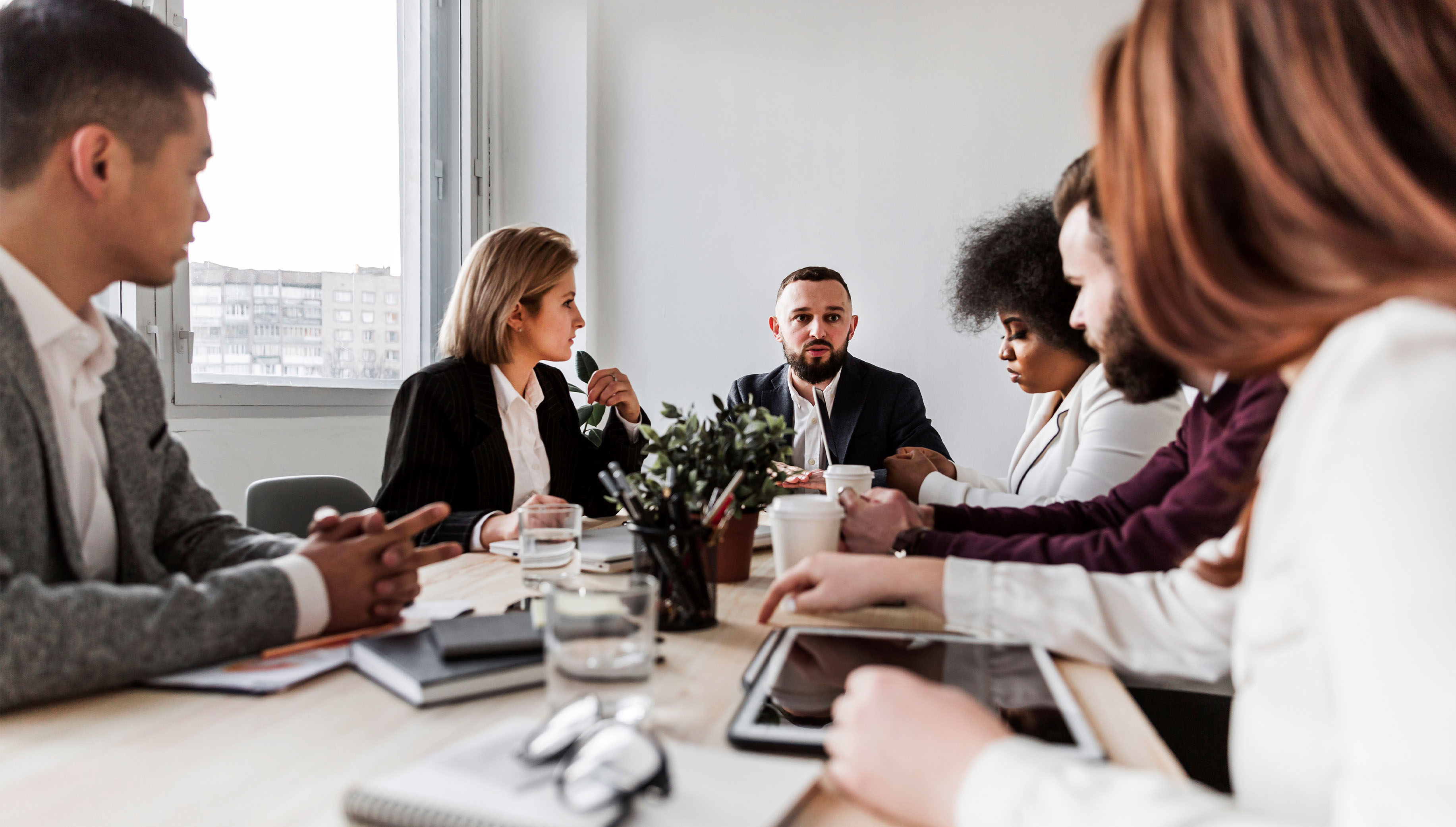 Profissionais em reunião de trabalho ao redor de uma mesa de madeira.