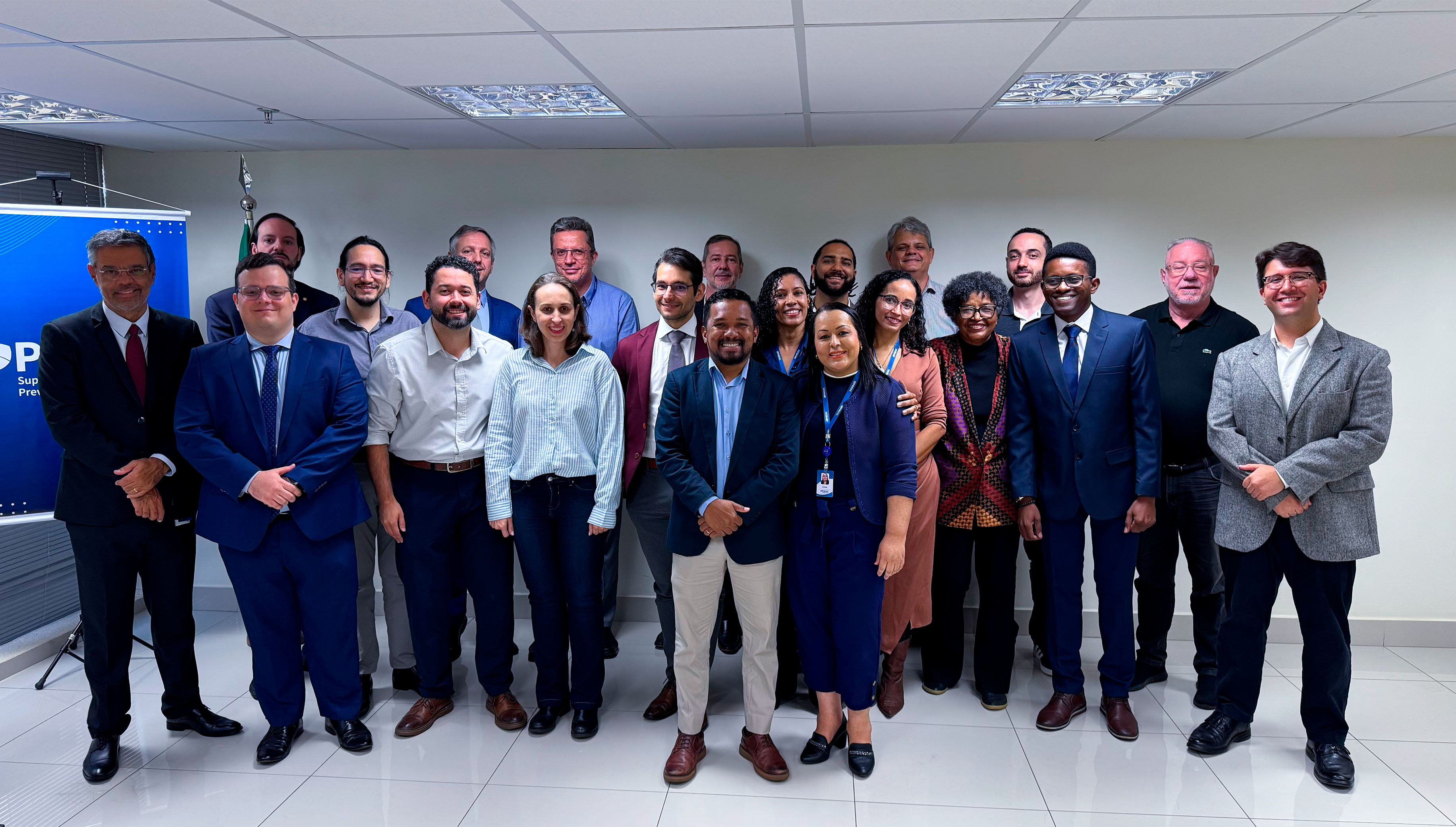 Grupo de servidores da PREVIC e novos empossados do CPNU sorriem juntos em foto institucional.