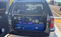 A imagem mostra o porta-malas aberto de um veículo utilitário desportivo (SUV) de cor prata, completamente carregado com fardos e pacotes de drogas.