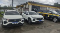 A imagem apresenta dois carros idêncitoc s ao lado de uma viatura da PRF