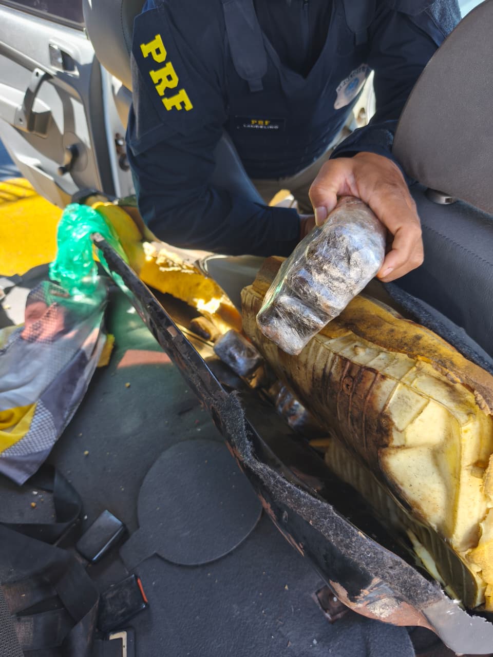 Policial retira volume ilícito oculto no interior de banco automotivo.