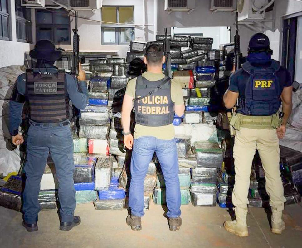 A imagem mostra policiais da PRF, PF e PM na frente de tabletes de droga