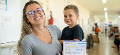 Moça com criança no colo para recebimento de imunização da meningite.jpeg