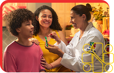 Uma profissional de saúde demonstra para uma criança e um adulto como escovar os dentes corretamente