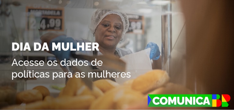 Mulher de touca, avental e luvas enchendo uma sacola com pães numa padaria