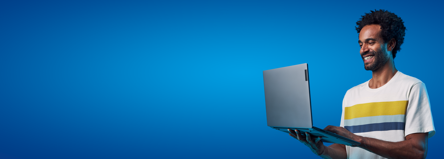 Imagem ilustrativa de um homem adulto que sorri enquanto mexe em um notebook sobre um fundo azul