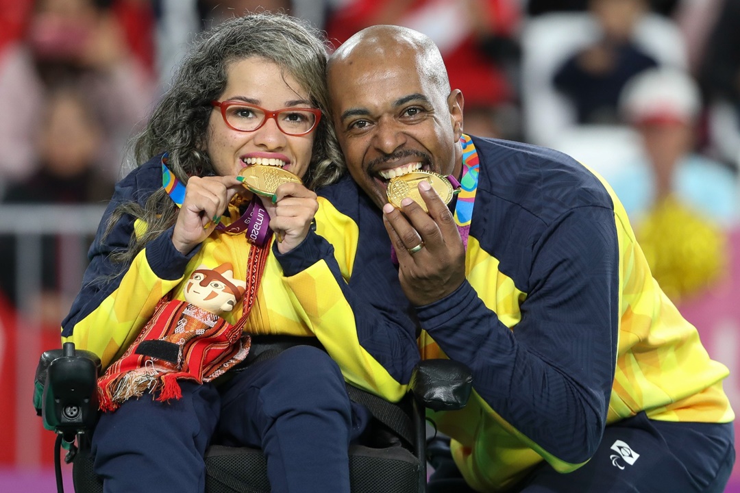 O calheiro Roberto Ferreira ao lado da atleta Evelyn Oliveira, da bocha. De costas para o jogo, ele ajusta a calha para os lançamentos da parceira. Foto: Daniel Zappe/EXEMPLUS/CPB