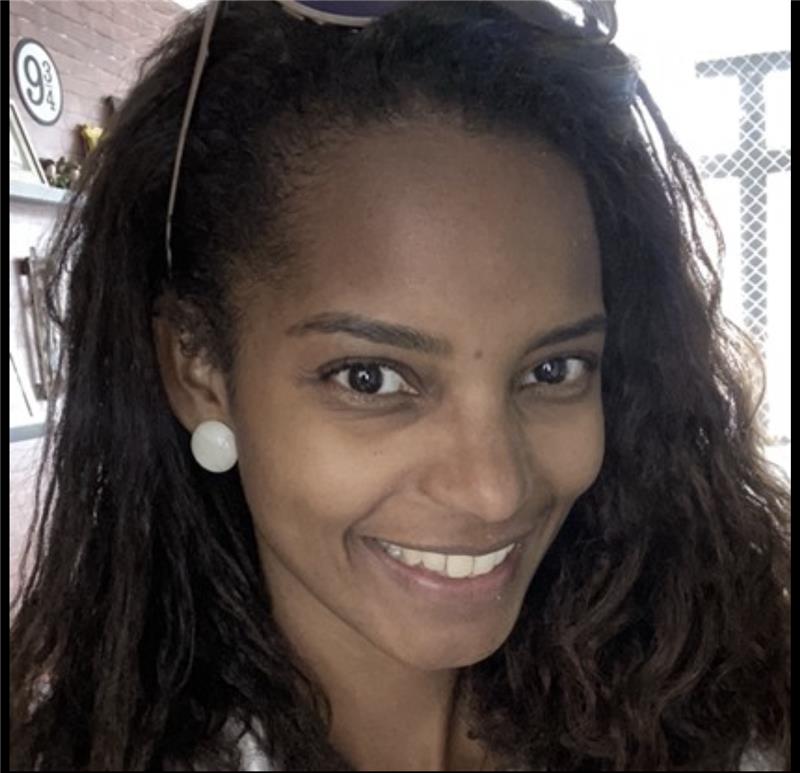 Mulher preta, cabelos cacheados, alisados até a altura dos ombros, lábios finos, nariz alongado com a ponta para baixo