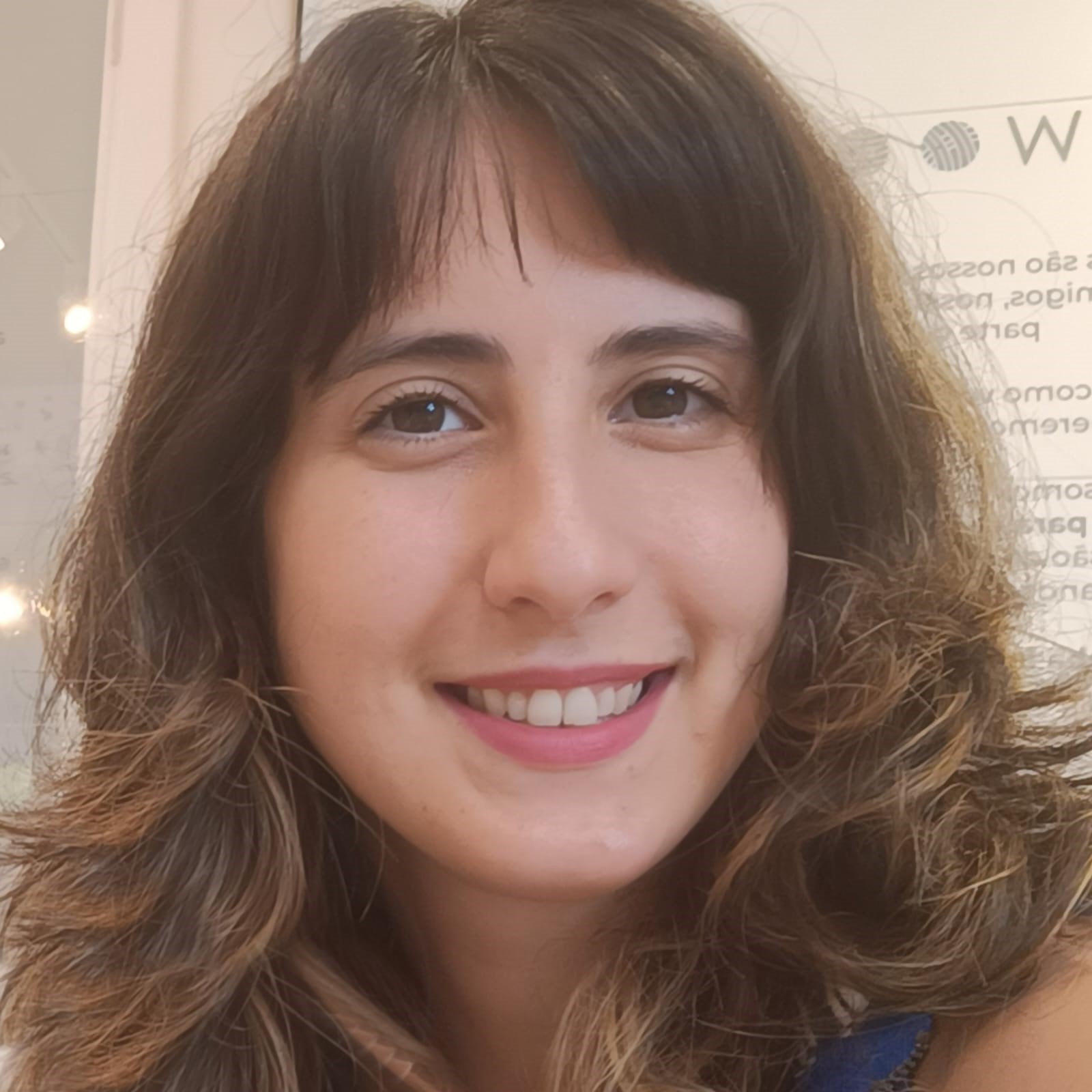 Mulher branca, cabelos castanhos longos de franja sorrindo