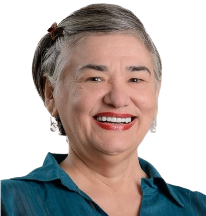 mulher branca, cabelos lisos, castanho claros nos ombros. Sorri para a foto e veste uma camiseta laranja. Em seu fundo, uma parede branca.