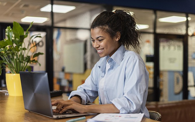 Mulher sorrindo utilizando um notebook