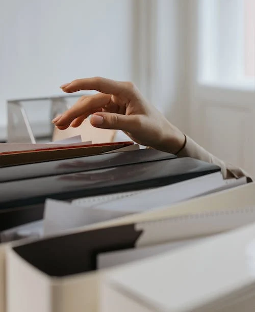 Uma mão a pegar algum documento em um arquivo com várias pastas