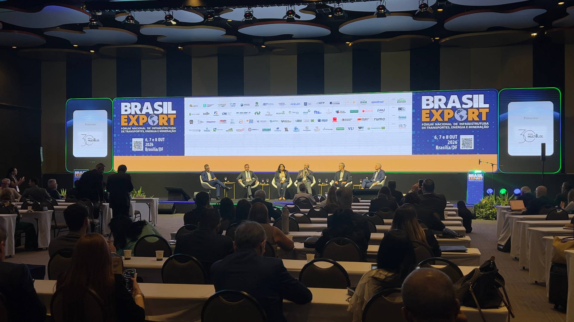 Auditório com os cinco painelistas e o mediador sentados em frente a uma plateia.
