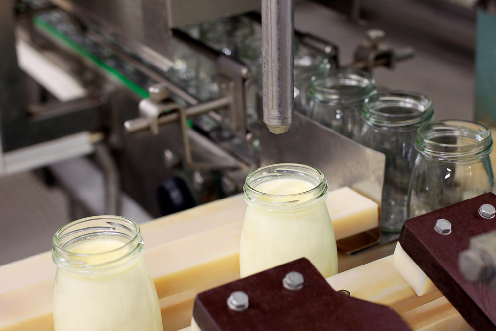 Imagem em detalhe de uma linha de produção de uma fábrica de laticínios.