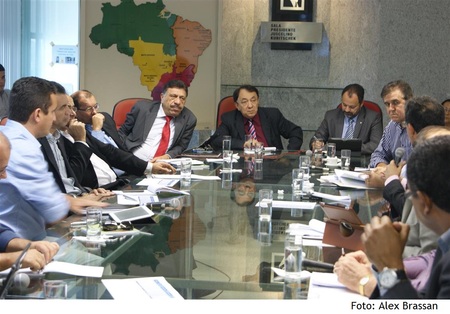 Várias pessoas sentadas ao redor de uma mesa conversando entre si.