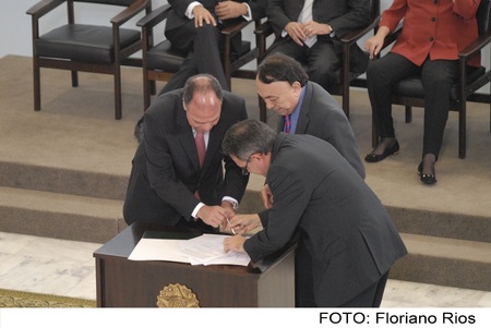 Superintendente Paes Landim ao lado de mais duas pessoas assinando um documento.