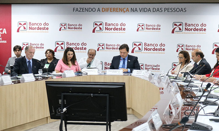 Foto da Mesa de reunião, com destaque para o superintendente da Sudene, Marcelo Neves. Ao seu lado, parte dos conselheiros. Atrás do superintendente aparecem outras pessoas que participaram do encontro
