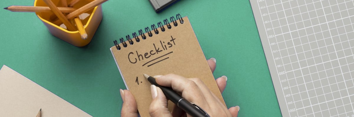 Imagem mostra uma mão segurando um bloco de anotações e outra segurando uma caneta.