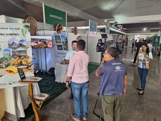 Foto mostra repórter ouvindo pessoa em uma feira