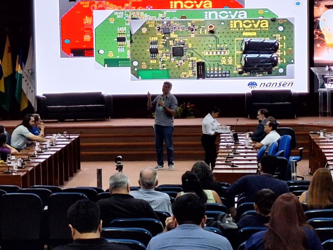 Foto mostra homem falando em evento, com o apoio de um telão