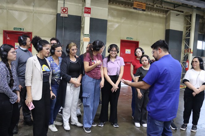 Foto mostra um homem de vestido de roupa azul fazendo uma explicação a um grupo de pessoas