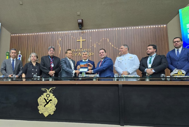 Foto mostra homens segurando uma placa comemorativa