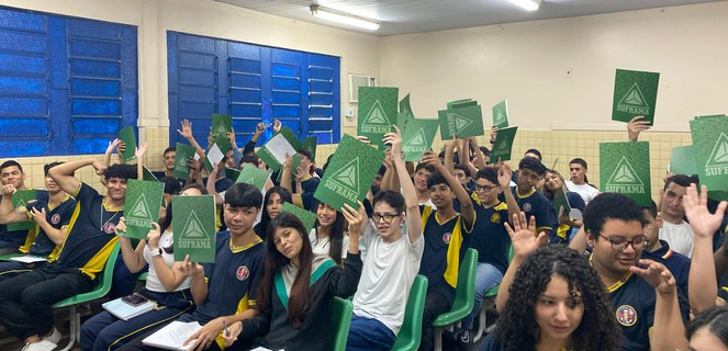 Foto mostra grupo de estudantes mostrando pasta na mão da cor verde e com a palavra Suframa