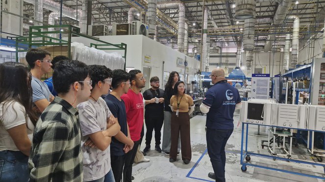 Foto mostra homem de blusa azul fazendo uma explicação a um grupo de alunos