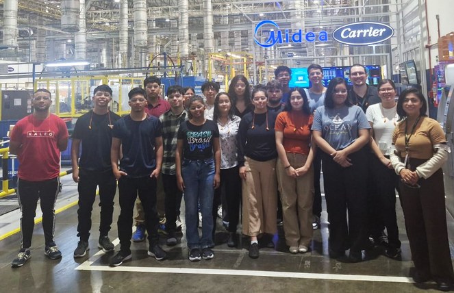 Foto mostra grupo de pessoas posando para foto dentro de uma fábrica