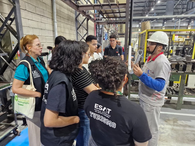 Foto mostra homem mostrando uma peça de bicleta a gupo de pessoas