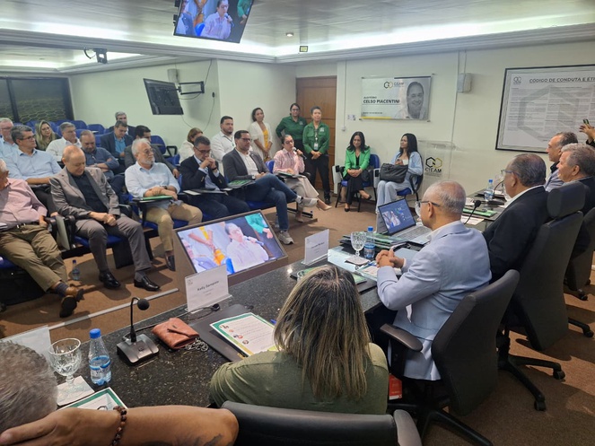 Foto mostra mulher falando durante evento em um auditório com várias pessoas presentes