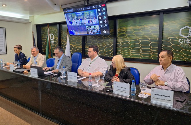 Foto mostra autoridades sentadas participando de um evento