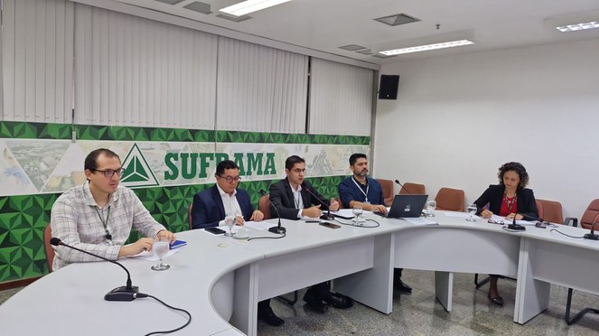 Foto mostra pessoas sentadas à mesa numa reunião