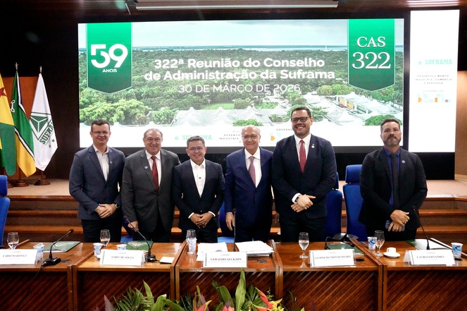 Foto mostra pessoas em pé com um telão ao fundo