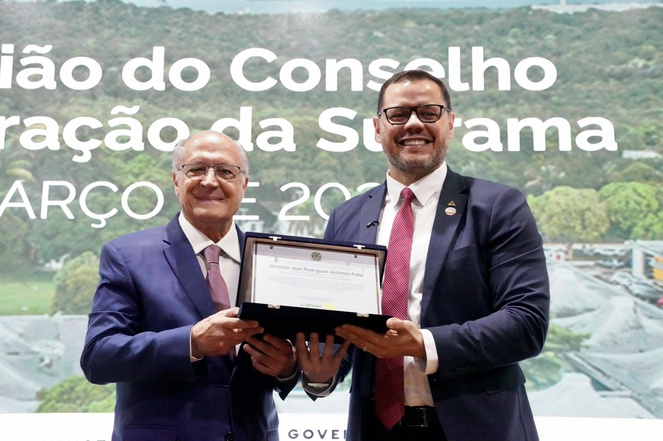 Foto mostra dois homens segurando uma placa