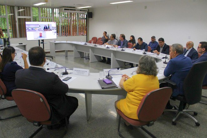 Foto mostra reunião em uma sala ampla com várias pessoas
