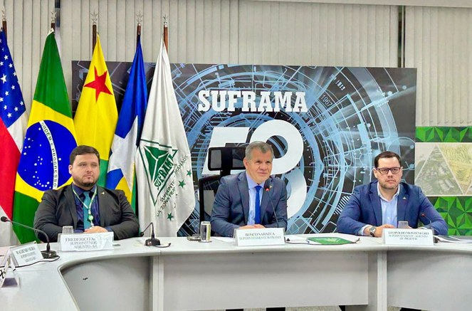 Foto mostra homem de paletó e gravata falando ao microfone durante reunião