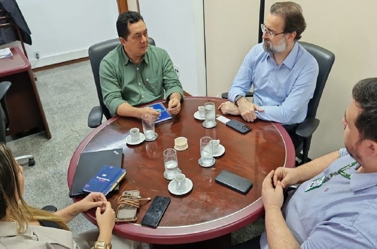Foto mostra pessoas sentadas em uma reunião institucional