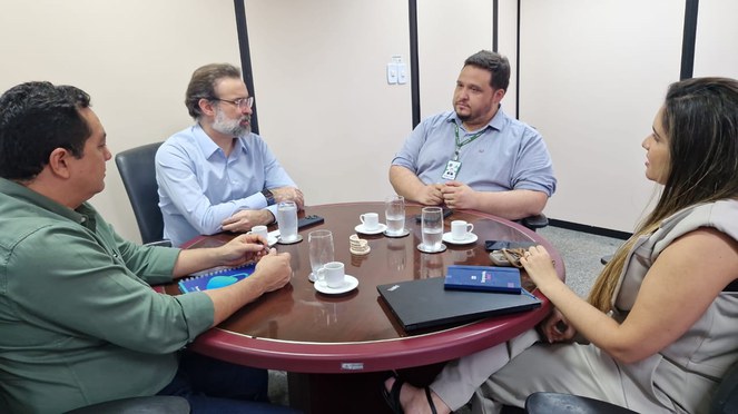 Foto mostra pessoas à mesa em reunião institucional