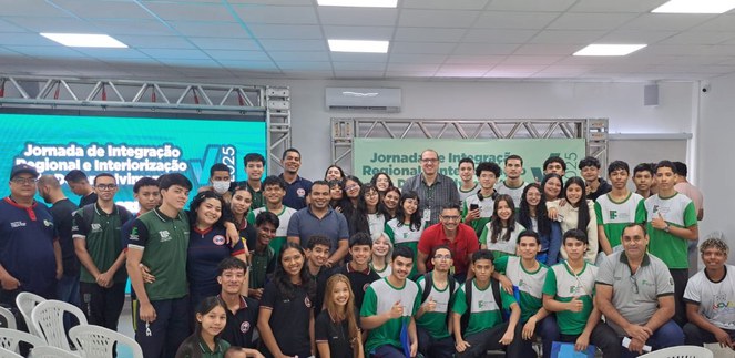 Foto mostra grupo de pessoas posando para sessão de foto com telão ao fundo