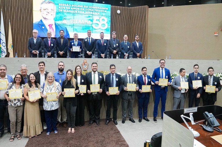 Foto mostra grupo de pessoas segurando certificados durante uma homenagem institucional