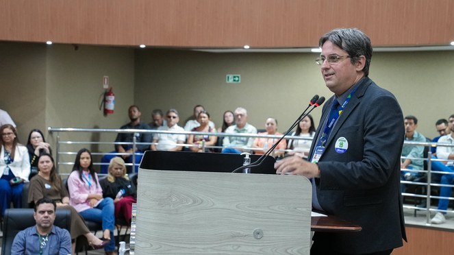 Foto mostra homem de paletó escuro em pronunciamento