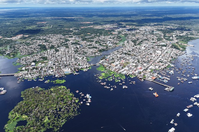 Foto mostra uma cidade do alto com rio e imóveis