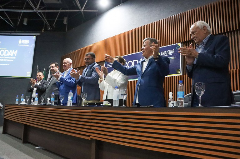 Foto mostra pessoas batendo palmas e celebrando em evento concorrido