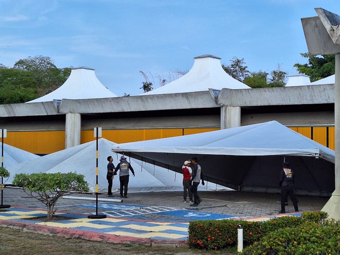 Foto mostra homens erguendo tendas para um evento