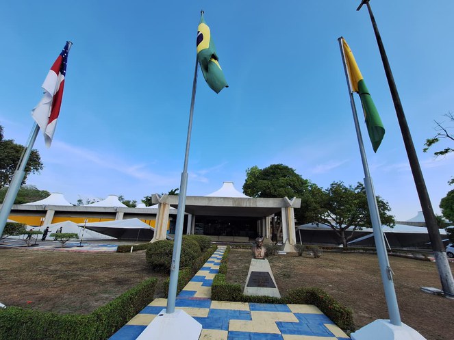 Foto mostra fachada de um imóvel com bandeiras na fachada e tendas sendo armadas ao fundo