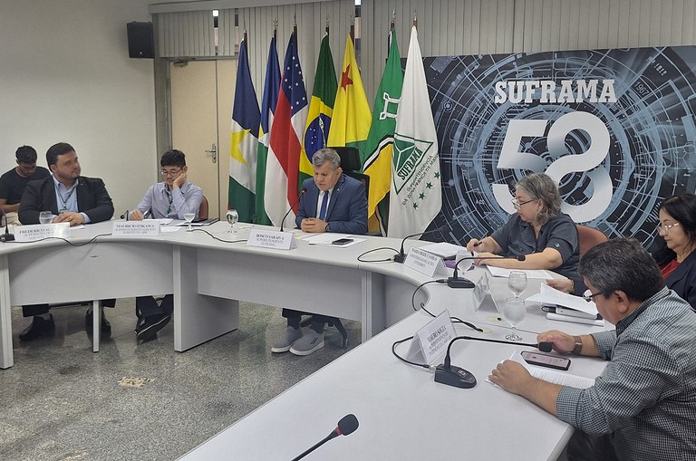 Foto mostra homem de blazer e gravata azul falando numa reunião