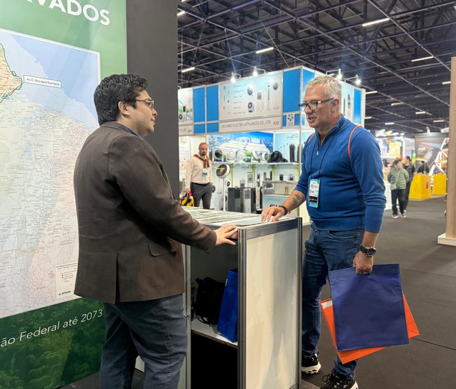 Foto mostra homem atendendo outro homem em um estande armado numa feira de eletroeletrônicos