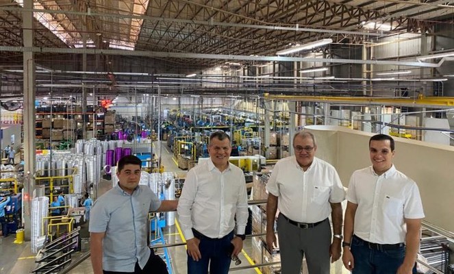 Foto mostra homens posando foto dentro de uma fábrica