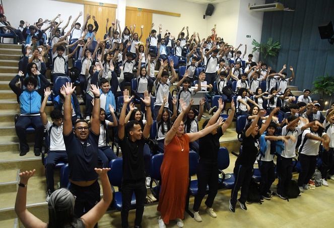 Foto mostra pessoas se movimentando em um auditório